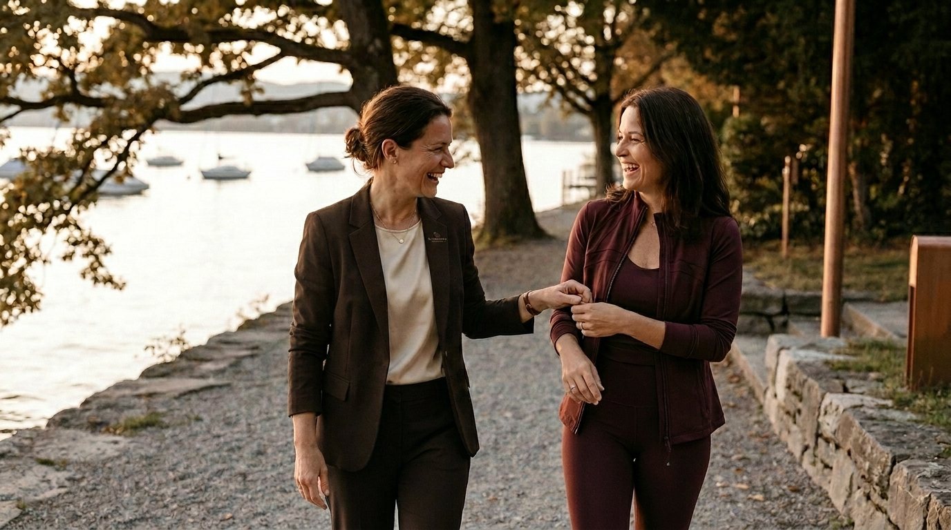 Zwei Frauen im Gespräch am Zürisee im warmen Abendlicht — Begleitung auf Augenhöhe, Segelboote und herbstliche Bäume am Ufer.